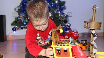 Un enfant joue avec un cadeau de Noël. (TIM SOMERSET / MAXPPP)